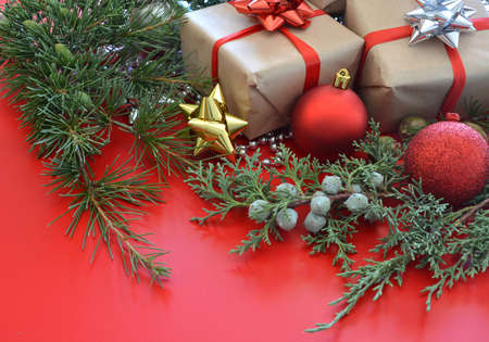 Christmas decorations accompanied by gifts, pines and balls on wooden tableの写真素材