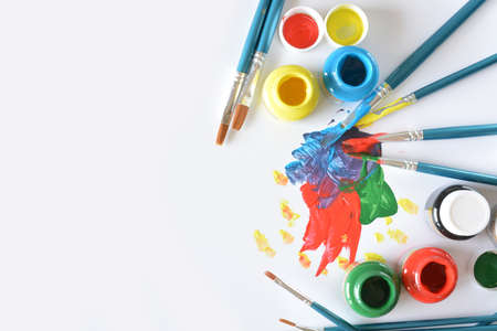 watercolors and brushes with children's drawings on white canvasの写真素材