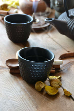 cups of black tea accompanied by incense , cinnamon and candlesの写真素材