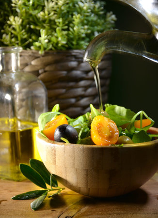 Olive oil falling on two olive with olive leaves to flavor a Mediterranean salad .Typical dish of the Mediterranean dietの写真素材