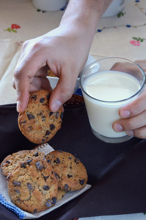hand dunking a cookie into a glass of milk