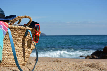 Beach bag with a book and a telephone and sunglasses accompanied by a sea starの写真素材