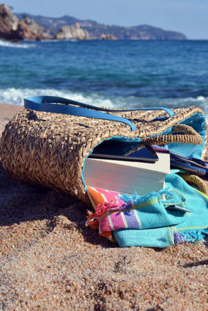 Beach bag with a book and a telephone and sunglasses accompanied by a sea starの写真素材