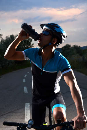 cyclist going mountain bike along a lonely road at sunsetの写真素材