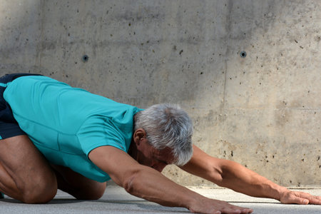 Older man practicing stretching on the street.