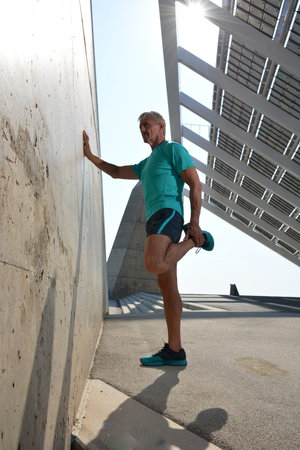 Older man practicing stretching on the street.の写真素材