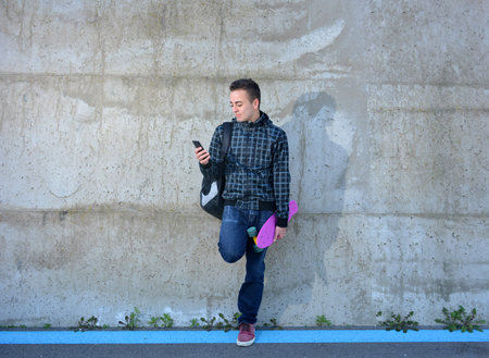 teen with skate watching your smarphone in the street
