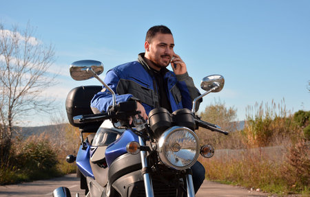 Biker talking by phone with his smarth phone in a road alone