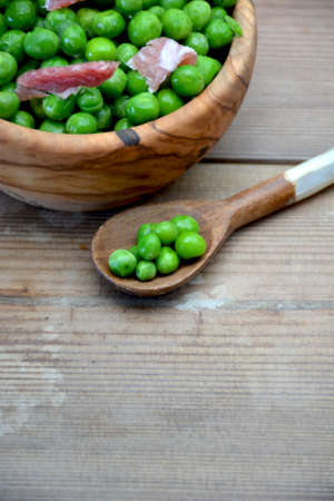 DISH OF WOOD FULL OF PEAS WITH HAM ON TABLE RUSTICの写真素材