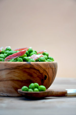 DISH OF WOOD FULL OF PEAS WITH HAM ON TABLE RUSTICの写真素材