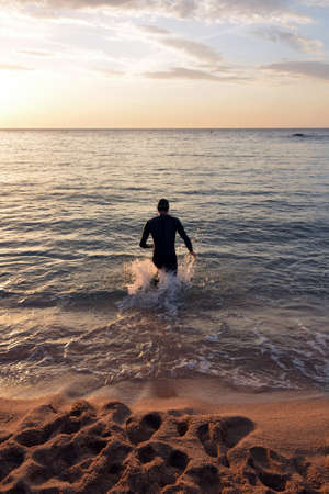 young athlete triathlon in front of a sunrise over the seaの写真素材
