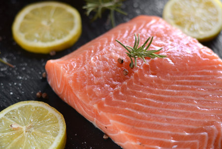Raw salmon fillets served with lemon, pepper and rosemary leaves 