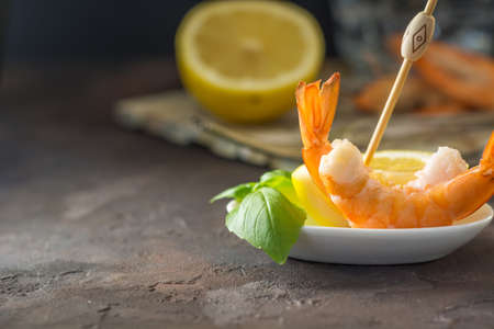 Appetizer of fresh prawns accompanied by lemon and put in a glass dishの写真素材