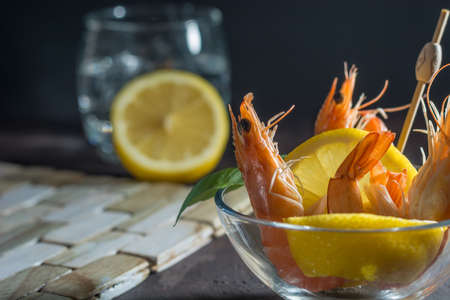 Appetizer of fresh prawns accompanied by lemon and put in a glass dishの写真素材