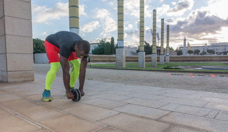 man training the abdominal muscles with the wheel in the park
