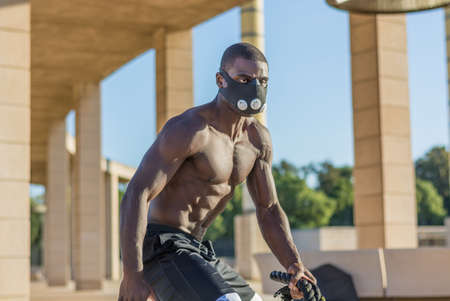 male muscular training with battle ropes and training mask in a park outdoorの写真素材