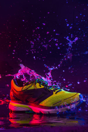 sports footwear on a black background and with splashes of waterの写真素材