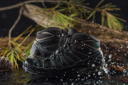 Black hiking boots, wet by a puddle of water on the mountainの写真素材
