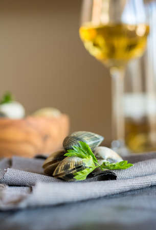 Wooden Bowl full of clams live, ready to be cooked. Background we found a bottle of white wineの写真素材