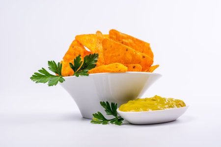 Plate full of nachos with guacamole on a white background