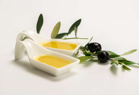 small dish full of olive oil and accompanied by some branches of a forgot with olivesの写真素材