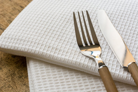 fork and knife with wooden handle on some cloth napkins and a wooden tableの写真素材