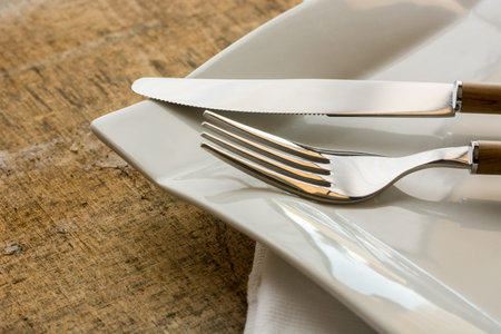 fork and knife with wooden handle on some cloth napkins and a wooden table