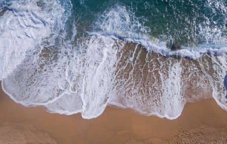 Aerial view of a paradisiacal beach with waves large on a sunny dayの写真素材