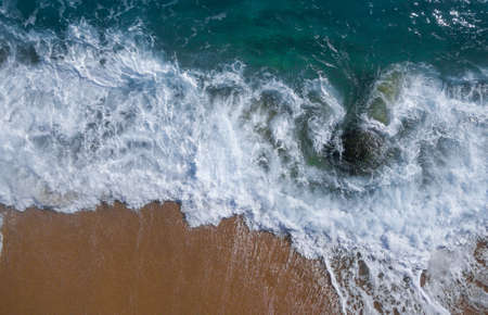 Aerial view of a paradisiacal beach with waves large on a sunny dayの写真素材