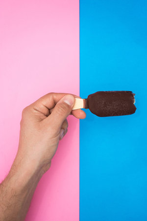 hand holding a chocolate and mint ice cream, with two colors, blue and pink background.