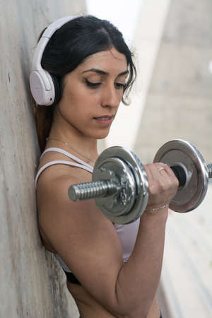 Fitness woman training outdoors and doing abdominal exercises and dumbbells in a street of Barcelonaの写真素材