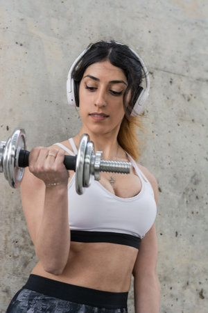 Fitness woman training outdoors and doing abdominal exercises and dumbbells in a street of Barcelona