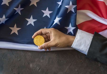 Bitcoin of gold in the hands of an executive with the flag of the United Statesの写真素材