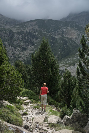 Woman hiking with a straw hat and backpack through the Spanish Pyrenees