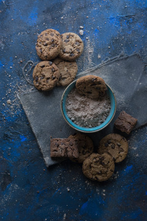 fresh homemade chocolate cookies on a baking tray accompanied by a cup of milk