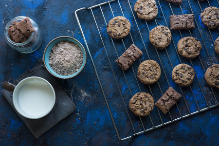 fresh homemade chocolate cookies on a baking tray accompanied by a cup of milk