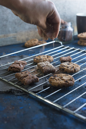 fresh homemade chocolate cookies on a baking tray accompanied by a cup of milk