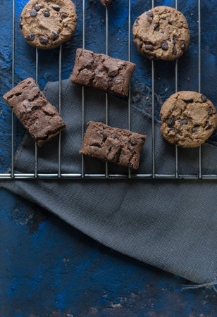 fresh homemade chocolate cookies on a baking tray accompanied by a cup of milk