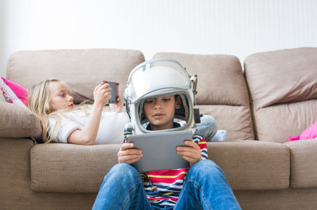 Children happily playing video games on the home sofa