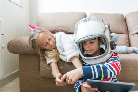 Children happily playing video games on the home sofa