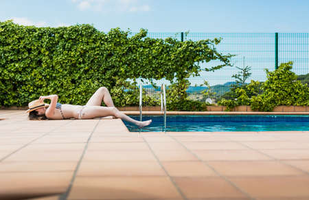 16 year old girl sunbathing peacefully in the pool of her house one summer afternoonの写真素材