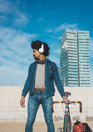 Man with afro hair riding a vintage style bicycle in the city to go to workの写真素材