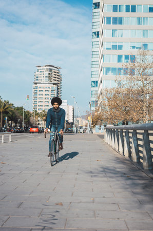 Man with afro hair riding a vintage style bicycle in the city to go to work