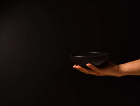 Man's hand on a black background with a plate of food in his hand.の写真素材
