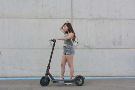 Teenage girl circulating with an electric scooter through the cityの写真素材