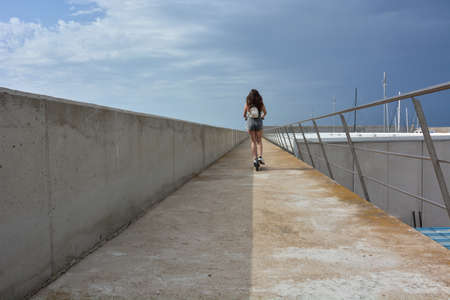 Teenage girl circulating with an electric scooter through the cityの写真素材