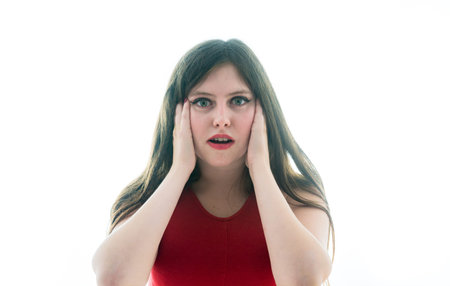 Portrait of a 17 year old adolescent girl with an unpleasant surprise face on a white background.
