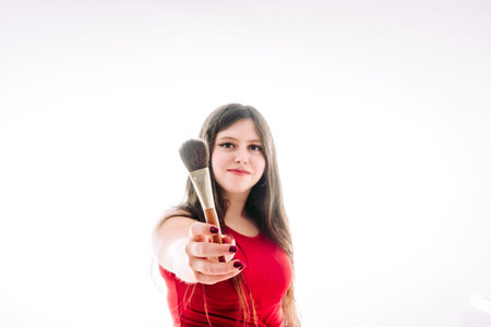 Teenage girl showing us her products to make up better. She shows us her brushes, lip glosses and lipsticks.の写真素材