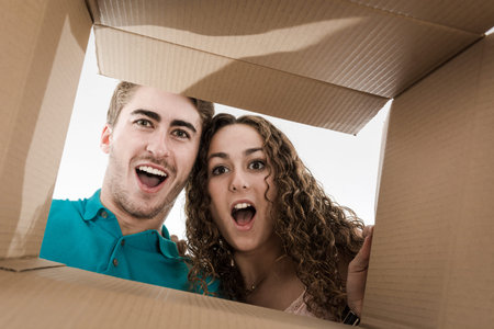 Couple opening cardboard box very happy with what's inside the box.