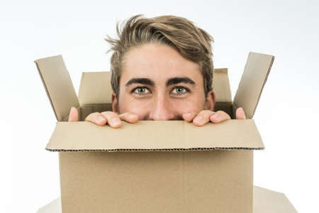 Boy with a face of surprise with his head inside a cardboard box.の写真素材